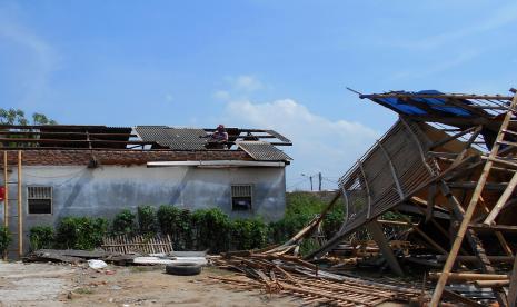 Warga memperbaiki atap rumah yang rusak pascaditerpa angin puting beliung