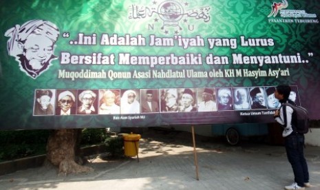 Warga memperhatikan foto sejumlah tokoh NU pada baliho Muktamar ke-33 Nahdlatul Ulama yang terpasang di Ponpes Tebuireng, Jombang, Jawa Timur, Ahad (26/7). 