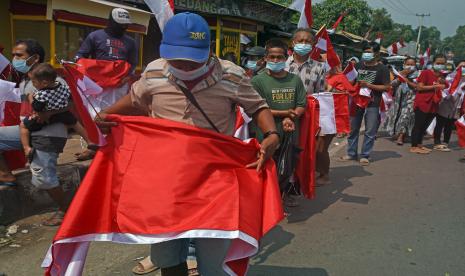 Warga memperlihatkan Bendera Merah Putih saat acara pembagian bendera di Kawasan Pemerintahan Provinsi Banten, di Serang, Selasa (9/8/2022). Menyambut HUT ke-77 Kemerdekaan RI pemerintah tengah menggulirkan Gerakan Nasional Pembagian 10 juta Bendera Merah Putih dengan tujuan untuk meningkatkan kesadaran kebangsaan di kalangan masyarakat sekaligus untuk memeriahkan momen bersejarah tersebut.