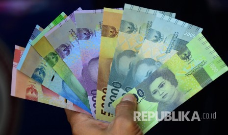 Warga memperlihatkan lembaran uang rupiah baru 