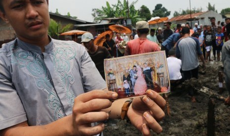 Warga memperlihatkan sebiah foto keluarga yang menjadi korban pembunuhan saat pemakaman di Medan, Sumatera Utara, Senin (10/4).