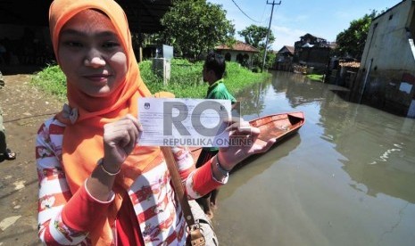 Warga memperlihatkan surat pemberitahuan pemungutan suara saat mengikuti pemilihan Kepala Daerah periode 2015-2020 di Cieunteung, Kabupaten Bandung, Rabu(9/12). (Republika/Septianjar Muharam)