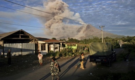  Warga memulai aktivitas mereka di pagi hari ketika Gunung Sinabung menyemburkan debu vulkanik di Desa Perteguhen, Karo, Sumut, Senin (6/1).    (AP/Binsar Bakkara)