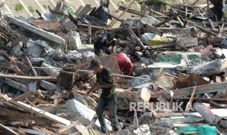 Warga memungut besi sisa bangunan usai gusuran di Bukit Duri, Jakarta, Kamis (29/9).