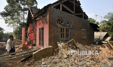 Warga memungut tiang kayu rumahnya yang rusak akibat diguncang gempa di Kampung Karoya, Mandalawangi, Pandeglang, Banten, Sabtu (3/8/2019).