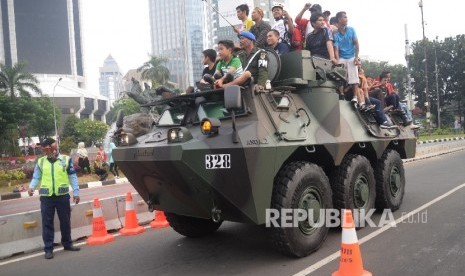  Warga menaiki kendaraan Anoa dalam Pameran Industri Pertahanan saat melintasi Jalan Merdeka Barat, Jakarta, Ahad (13/8). Pemerintah melalui Kementerian BUMN memiliki target pembentukan Holding BUMN Industri Pertahanan pada tahun 2021.