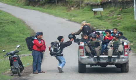 Warga menaiki mobil bak terbuka untuk mengungsi dengan penjagaan aparat keamanan di Bandara Ilaga, Kabupaten Puncak, Papua, Selasa (1/10/2019).