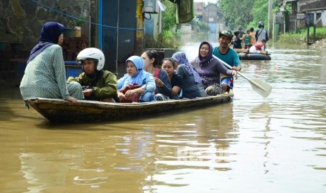 Warga menaiki perahu, di jalan yang sudah terendam banjir. ilustrasi 