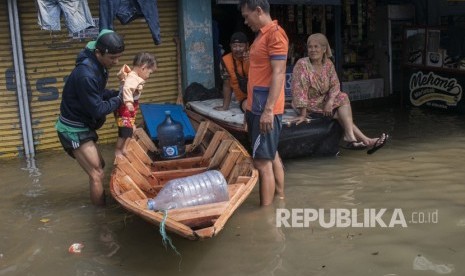 Warga menaikkan balita ke atas perahu untul melintasi genangan banjir luapan sungai Citarum di Kawasan Baleendah, Kabupaten Bandung, Jawa Barat, Jumat (5/4/2019). 