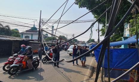 Warga menangani kabel jaringan internet yang terurai di jalan karena tersangkut truk pengangkut kaca di Kedaung, Tangerang Selatan, Banten, Rabu (27/7/2022). Kabel milik perusahaan penyedia jasa internet tersebut putus tersangkut truk karena kondisi kabel yang kendor dan semrawut. 