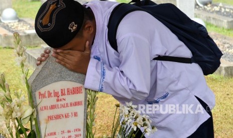 Warga mencium batu nisan makam BJ Habibie saat berziarah di Taman Makam Pahlawan Nasional Utama (TMPNU) Kalibata, Jakarta Selatan, Jumat (13/9/2019). 