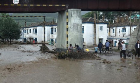 Warga mencoba membersihkan sampah yang terbawa banjir di bawah jembatan di Kota Rajin, Korea Utara, 22 Agustus 2015.