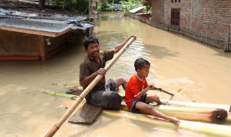 Warga mendayung perahu buatan saat berusaha keluar dari rumahnya yang terendam banjir di kawasan pemukiman penduduk bantaran Sungai Citarum, Kedungwaringin, Kabupaten Bekasi, Jawa Barat, Senin (14/11).