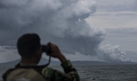 Warga mendayung sampan dengan latar belakang Gunung Anak Krakatau di Pelabuhan Pulau Sebesi, Lampung Selatan, Lampung.