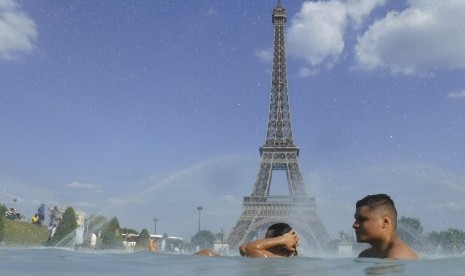 Warga mendinginkan diri di kolam air mancur Trocadero dengan latar belakang menara Eiffel di Paris, Prancis, Selasa (25/6). Gelombang panas menerjang Eropa. Suhu 45 derajat Celsius diperkirakan terjadi di Prancis.