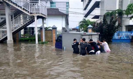 Warga mendorong mobil yang mogok di tengah banjir di Cempaka Putih, Jakarta, Kamis (17/1). 