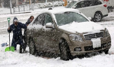  Warga mendorong mobil yang terdampar akibat hujan salju lebat di Tokyo,Senin (114/1).  (Reuters/Kim Kyung-Hoon) 