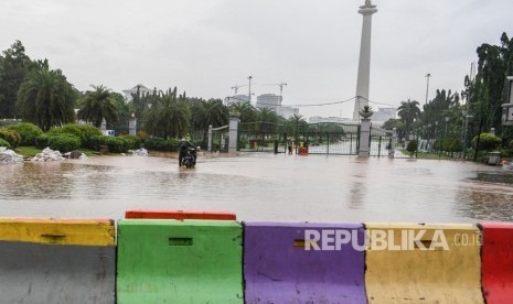 Warga mendorong motor melintasi banjir di kawasan Monas, Jalan Medan Merdeka Barat, Jakarta, Ahad (2/2/2020).