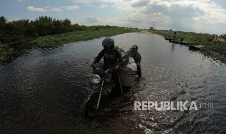 Warga mendorong motor yang mogok saat lewati jalan penghubung Desa Jebus dengan Desa Gedong Karya yang terendam banjir luapan Sungai Batanghari di Muarojambi, Jambi, Selasa (7/1/2020). 