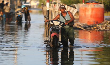 Warga mendorong motornya yang mogok akibat menerobos banjir rob (ilustrasi). BMKG memperingatkan masyarakat potensi banjir rob di sejumlah wilayah pesisir Indonesia selama libur Lebaran 2024.