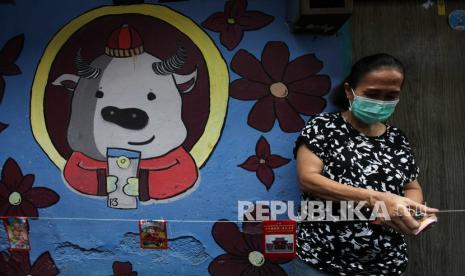 Warga menempelkan kertas angpao pada seutas tali sebagai dekorasi di kampung pecinan Tambak Bayan, Surabaya, Jawa Timur, Senin (31/1/2022). Dekorasi angpao yang dipasang di sepanjang jalan kampung itu untuk memeriahkan perayaan Tahun Baru Imlek.