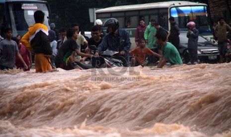   Warga menerobos arus deras air banjir yang menggenangi kawasan jalan Sudirman, Jakarta, Kamis (17/1).  (Republika/Yasin Habibi)