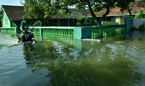 Warga menerobos banjir di depan MI Nidhomiyah Desa Jatigedong, Kecamatan Ploso, Jombang, Jawa Timur, Kamis (2/5/2019).