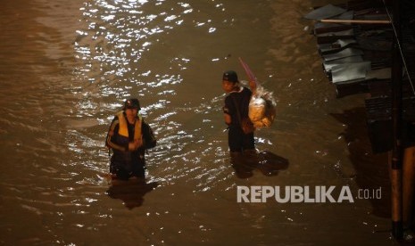 Warga menerobos banjir di kawasan Cililitan, Jakarta, Senin (5/2) malam. Banjir yang merendam kawasan tersebut akibat luapan Kali Ciliwung yang merupakan kiriman dari Bendung Katulampa, Bogor. 