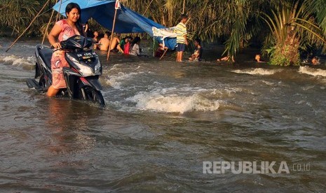 Warga menerobos banjir luapan Sungai Kampar yang merendam badan jalan di Desa Buluhcina, Kampar, Riau, Rabu (8/3). Meluapnya Sungai Kampar membuat ratusan rumah warga terendam