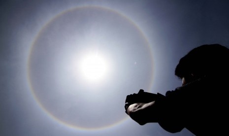 Warga mengabadikan fenomena Halo Matahari berbentuk cincin terlihat di atas langit kota Lhokseumawe, Aceh, , Kamis (30/3). 