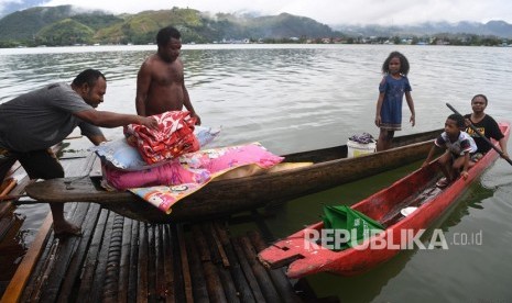 Warga mengamankan barang berharga miliknya dari rumahnya yang dilanda banjir bandang di kawasan Danau Sentani, Sentani, Jayapura, Papua, Selasa (19/3/2019). 