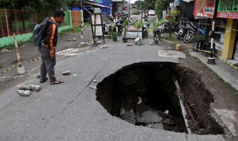 Warga mengamati jalan yang ambles di Jl. Babaran, Yogyakarta, Ahad (22/12).