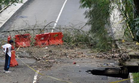 Warga mengamati jalan yang longsor di Jalan Tubagus Muhammad Falak, Kelurahan Loji, Kota Bogor, Jawa Barat, Kamis (20/10/2022). Perbaikan Jalan KH TB M Falak, Bogor akibat longsor akan dipercepat.