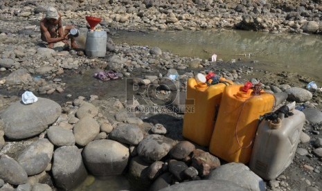 Warga mengambil air dari sumur buatan warga untuk kebutuhan rumah tangga di Kali Cipamingkis, Bekasi, Jawa Barat, (29/07).