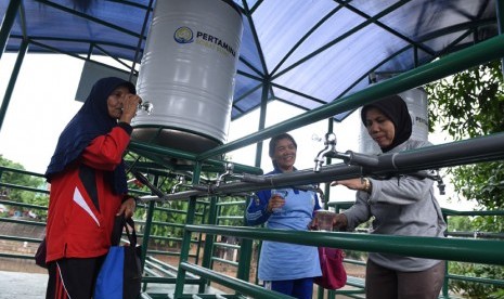 Warga mengambil air untuk diminum dari faslitas filter air bersih di Sungai Ciliwung kawasan Bidara Cina, Jakarta, Selasa (12/1).