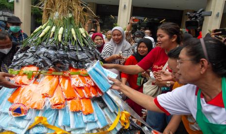 Warga mengambil masker di gunungan prokes saat larung gunungan di Teras Malioboro I, Yogyakarta, Selasa (11/10/2022). Larung gunungan prokes yang digelar BPBD DIY tersebut untuk mengingatkan kembali penerapan protokol kesehatan terutama bagi wisatawan di kawasan Malioboro. 