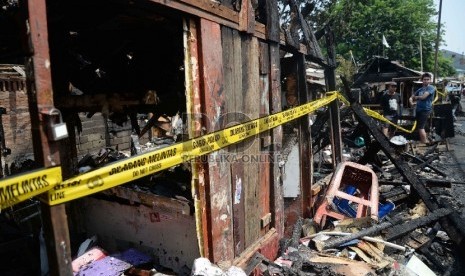 Warga mengambil puing sisa kios yang terbakar di Kawasan Pasar Poncol, Jakarta.