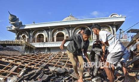 Warga mengangkat sepeda motornya dari reruntuhan rumah pascagempa di Desa Wadon, Kecamatan Gunungsari, Lombok Barat, NTB, Senin (6/8).