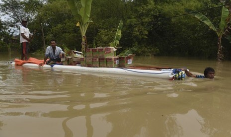 Warga mengangkut bantuan sembako di atas rakit melintasi banjir di Baureno, Bojonegoro, Jawa Timur, Jumat (2/12). 