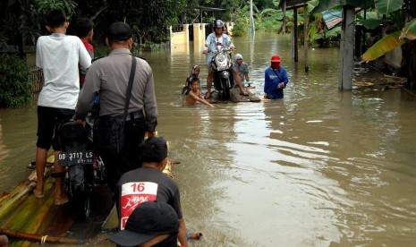 Warga mengangkut sepeda motor menggunakan rakit batang pisang saat banjir di Desa Panakkukang, Kabupaten Gowa, Sulawesi Selatan, Jumat (28/12/2018).