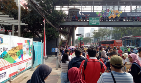 Warga mengantre untuk menggunakan JPO Halte GBK, Ahad (2/8).