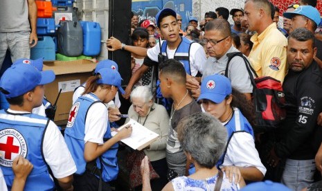 Warga mengantre air bersih dan pil pemurni air saat bantuan kemanusiaan pertama Palang Merah tiba di Caracas, Venezuela.