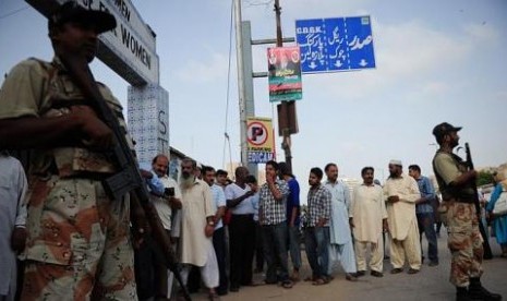 Warga mengantri untuk memberi suara di satu tempat pemungutan suara di Karachi dengan penjagaan tentara dalam pemilu nasional Pakistan pada Sabtu (11/5/2013)a Sabtu