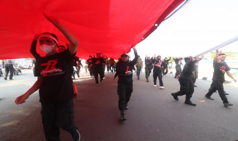 Warga mengarak kain warna merah dan putih melewati bangunan bersejarah Jembatan Lama, Kota Kediri, Jawa Timur, Selasa (16/8/2022). Kain yang terbagi dalam sejumlah potongan tersebut akan disatukan menjadi bendera merah putih raksasa selebar 35 meter x 55 meter dan akan dikibarkan pada tanggal 17 Agustus di atas pegunungan Klotok guna memperingati HUT ke-77 kemerdekaan RI.