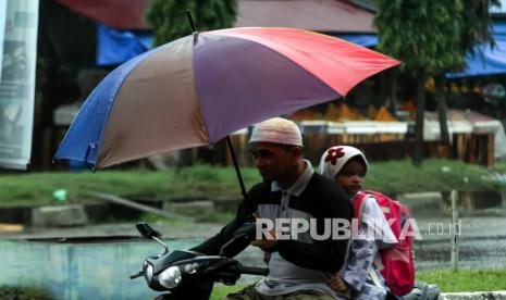 Warga mengendarai motor menerobos hujan. Waspada Curah Hujan Sangat Tinggi di Sebagian Wilayah NTT