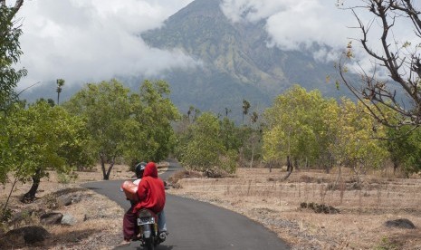 Warga mengendarai sepeda motor di Desa Datah yang berjarak sekitar 10 km dari Gunung Agung yang masih berstatus awas di Karangasem, Bali, Rabu (18/10). 