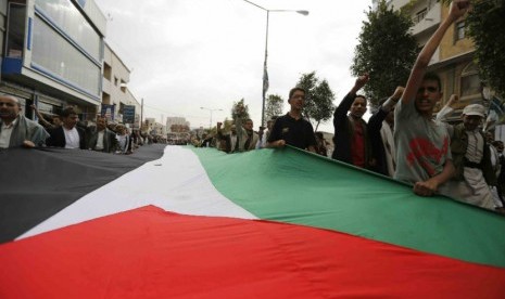 Warga menggelar bendera raksasa Palestina dalam aksi protes menentang serangan udara Israel di Sanaa pada Kamis (10/7). 