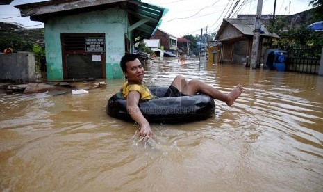  Warga menggunakan ban karet mencoba melintasi banjir luapan air sungai Ciliwung di Jalan H Bawah, Kelurahan Kebon Baru, Kecamatan Tebet, Jakarta Selatan, Rabu (22/1).   (Republika/Prayogi)