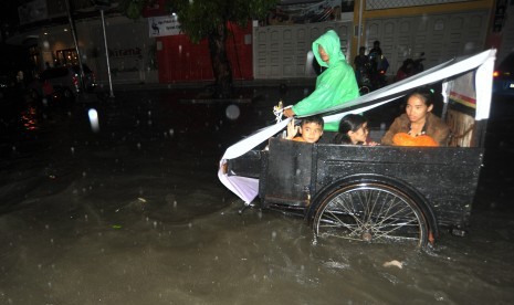 Warga menggunakan becak melintasi banjir di Jl Imam Bonjol, Padang, Sumatera Barat, Sabtu (9/9).