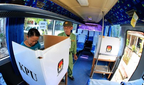 Warga menggunakan hak pilih di TPS yang menggunakan bus untuk bilik suara pada Pemilihan Kepala Daerah (Pilkada) Solo di Tempat Pemungutan Suara (TPS) 7 Tegalmulyo, Nusukan, Banjarsari, Solo, Jawa Tengah, Rabu (9/12).